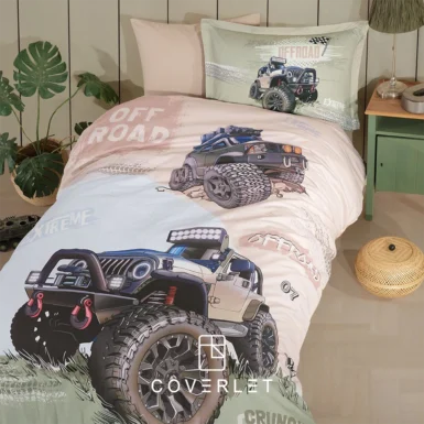 نمای نزدیک روتختی پسرانه آفرودی Off Road با چاپ جزئیات لاستیک‌های بزرگ، متن Off Road و روبالشتی ست در کنار میز چوبی و دکور اتاق پسرانه.